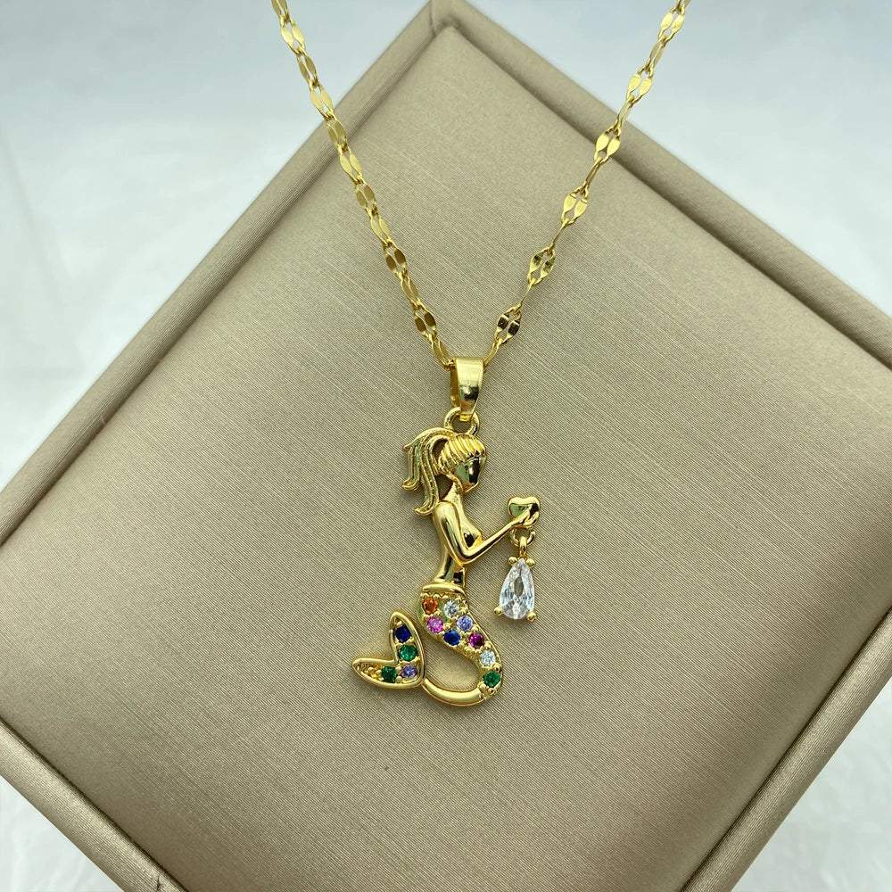 gold-tone mermaid pendant set with multicolored stones holding a dangling clear teardrop