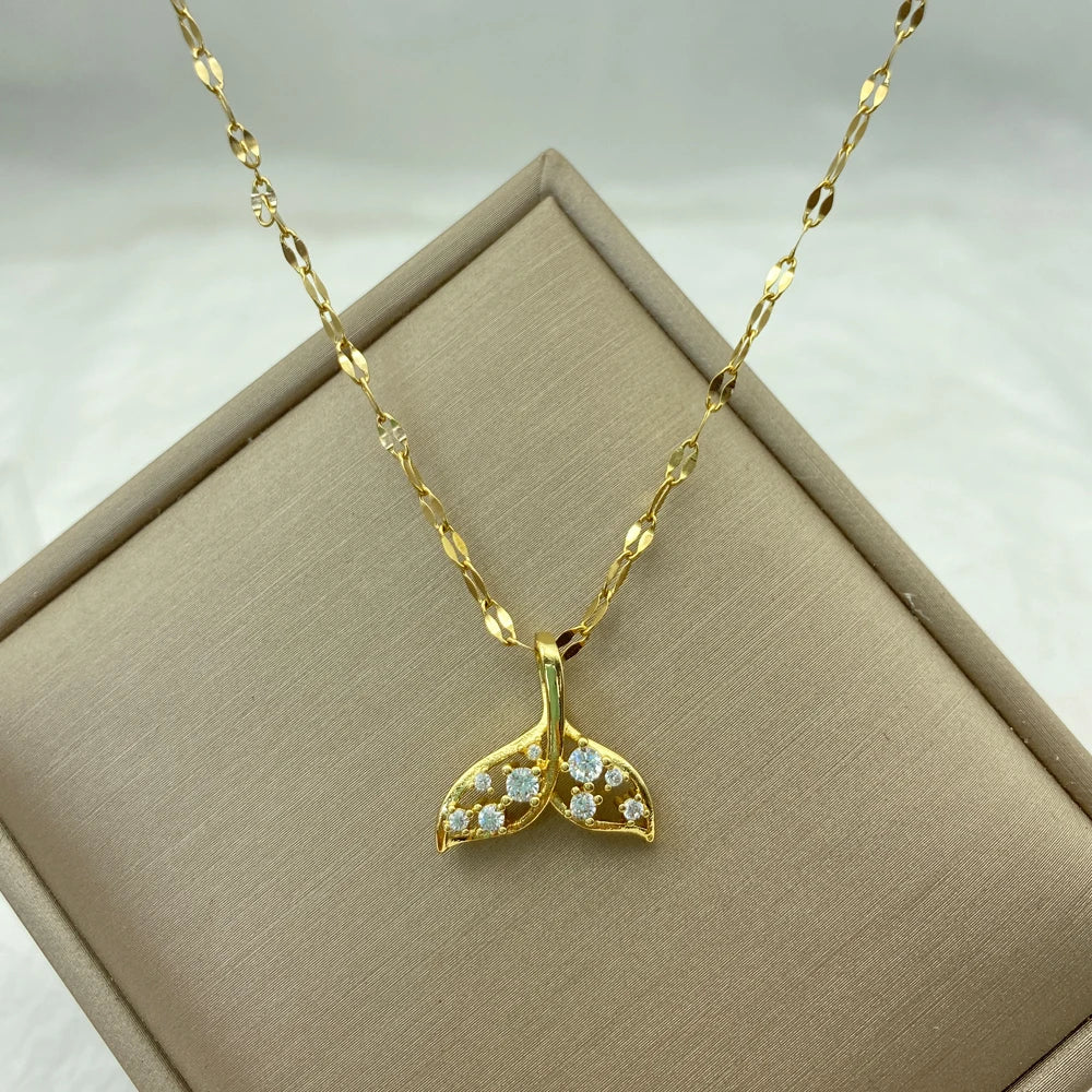 Gold-tone whale-tail pendant necklace accented with clear stones on a patterned chain