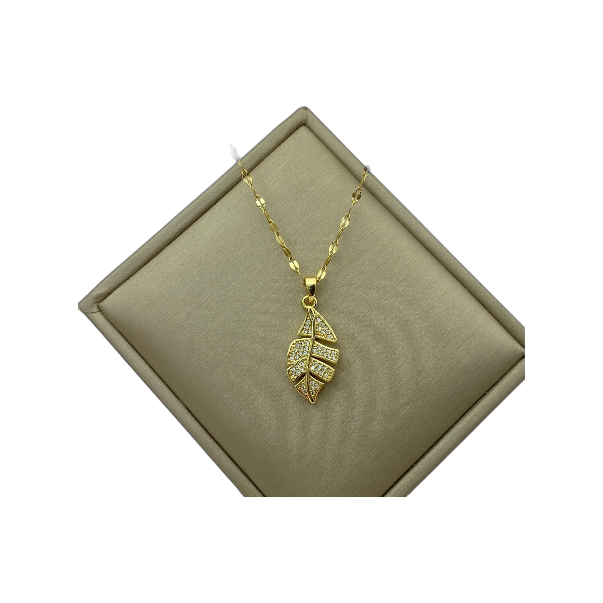 gold-tone leaf pendant necklace shown on a beige jewelry display box