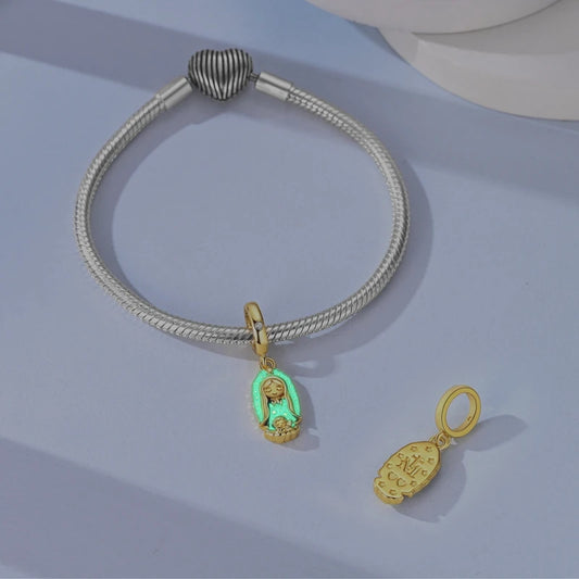 Gold-tone Madonna glow-in-the-dark dangle charm glowing green on a bracelet with a spare charm nearby
