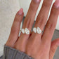 hand wearing gold-tone and silver-tone bypass rings with pear-cut stones on adjacent fingers