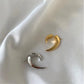 Gold-tone and silver-tone crescent claw earrings shown together on draped white fabric