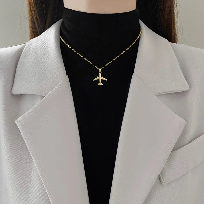 Gold-tone airplane pendant necklace worn at the collarbone