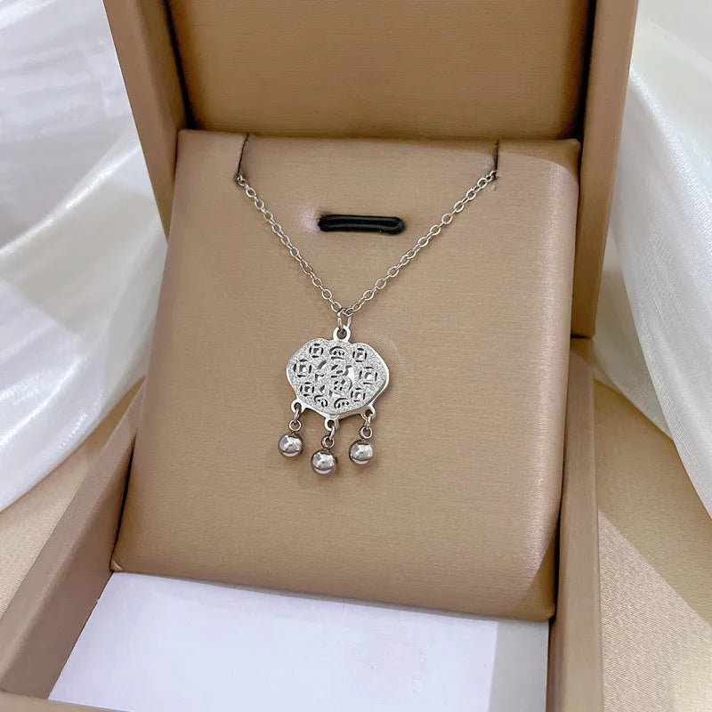 7d6c13ec-c91e-49f7-9ec7-8fd3145400b1 gold-tone filigree pendant with three dangling beads on beige display cushion