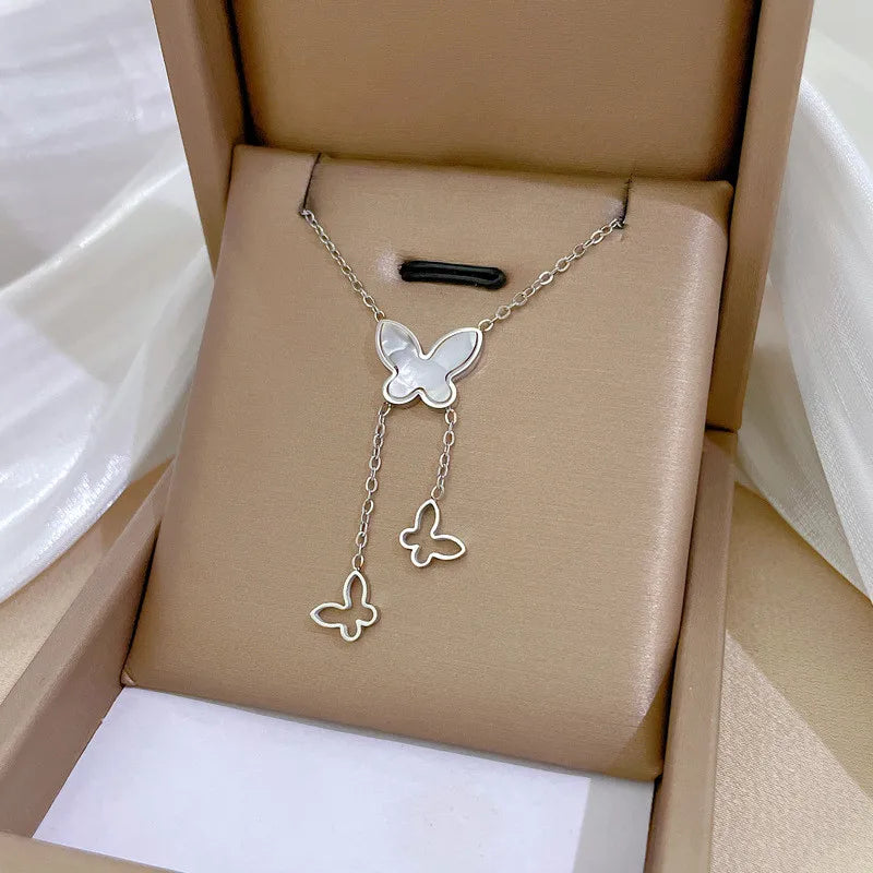 6fe1b986-7308-4eb8-9f7b-524bd9e2d2e0 silver-tone butterfly pendant with two dangling charms on box