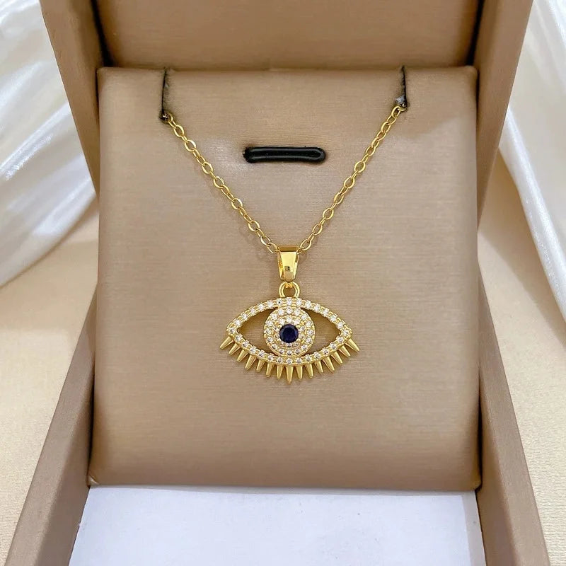 Decorative eye-motif gold-tone pendant with radiating fringe presented in a box