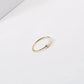Gold-tone thin stacking ring with irregular pearl beads photographed at an angle