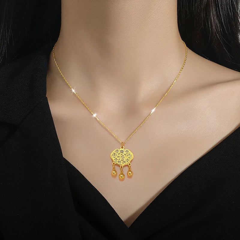 Gold-tone ornate heart pendant necklace with dangling charms worn at the collarbone