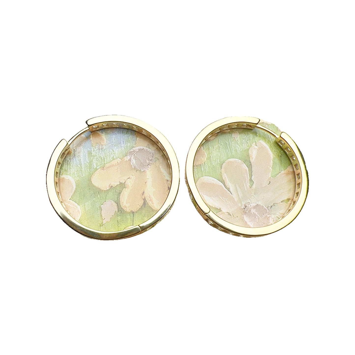 Gold-tone hinged hoops shown from the back with inner settings visible on a floral background