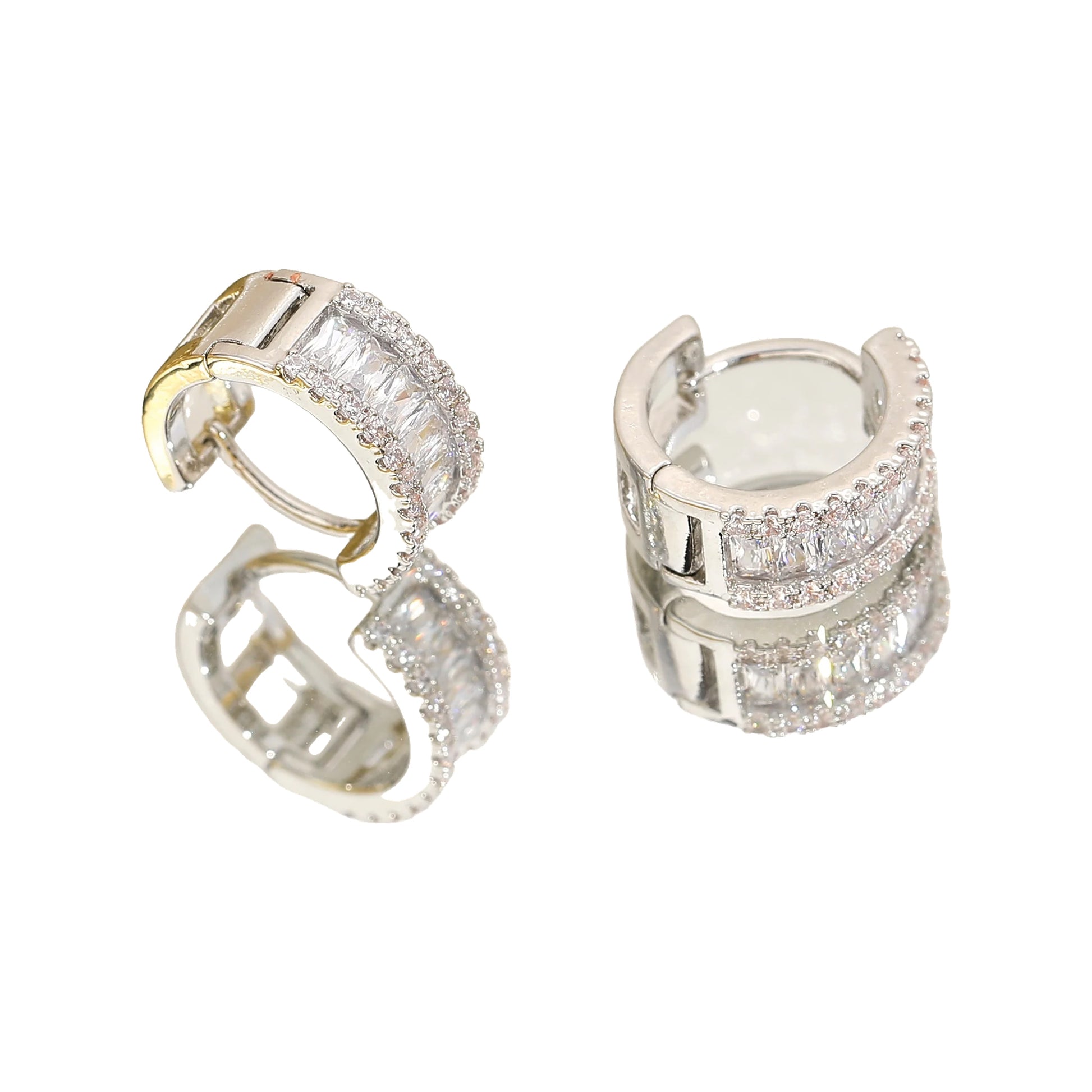 silver-tone baguette rhinestone huggie hoops on a mirrored surface with sheer fabric
