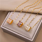 Three barrel pendant necklaces with baguette crystal rows in amber, purple, and clear on a display box, gold-tone chains
