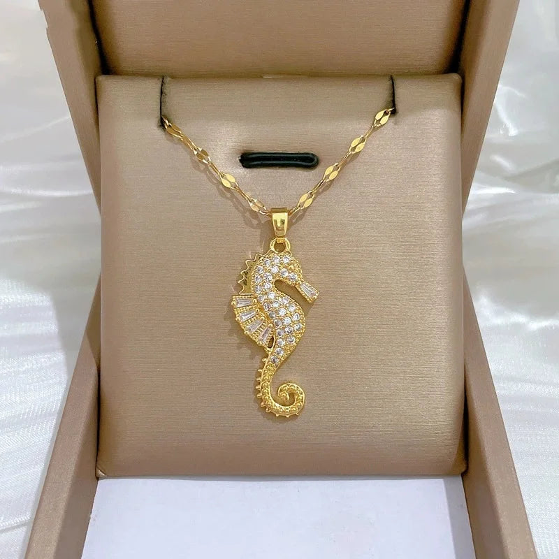 Gold-tone butterfly pendant necklace with clear stones and two dangling bars on a fine chain, displayed on a jewelry box.