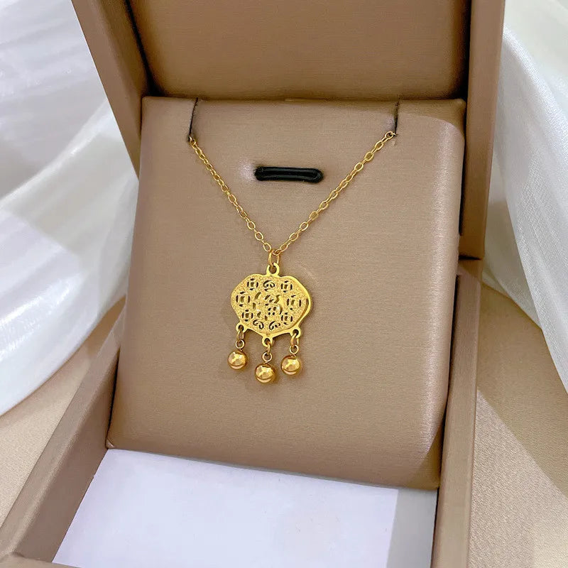 410f6869-5500-48f6-88e9-093730d7b1fc gold-tone bow pendant necklace worn at the collarbone on a black top