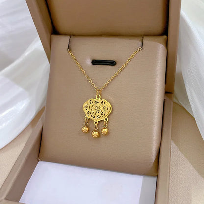 410f6869-5500-48f6-88e9-093730d7b1fc gold-tone bow pendant necklace worn at the collarbone on a black top
