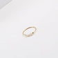 Gold-tone thin stacking ring with irregular pearl beads centered on white surface