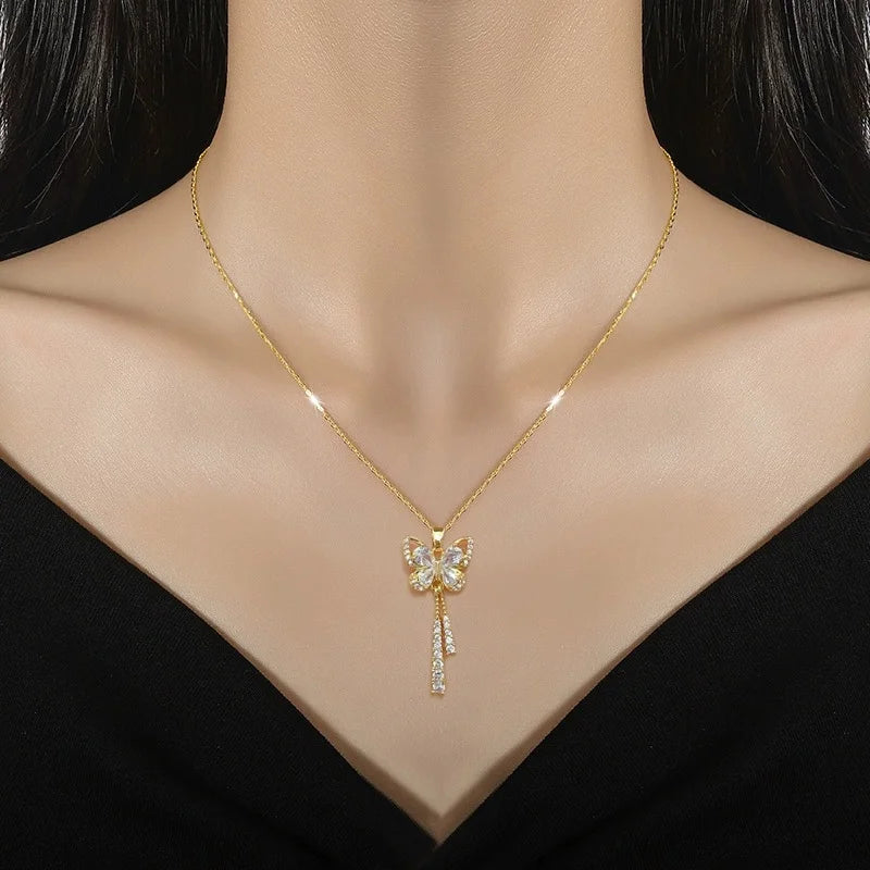 Gold-tone butterfly pendant with dangling accents worn at the collarbone
