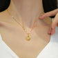 Model wearing a gold-tone scallop shell pendant necklace with pearl-like accent resting at the collarbone.