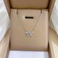 Silver-tone bow pendant necklace presented on a padded gift box