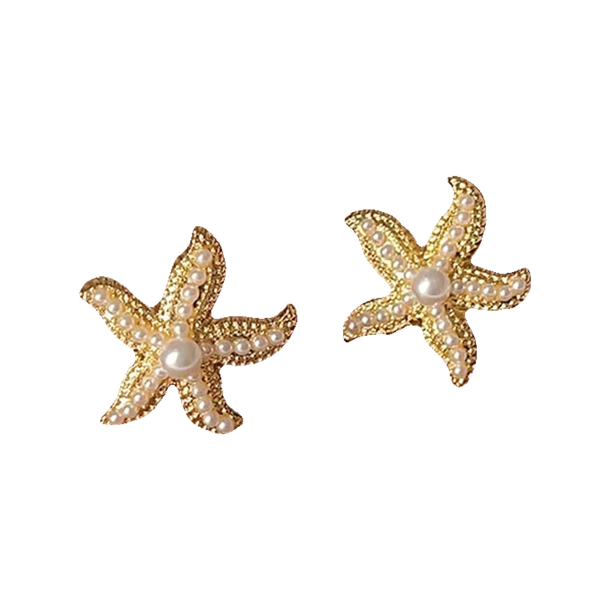 Gold-tone starfish studs with pearl beads displayed on a brown leather surface