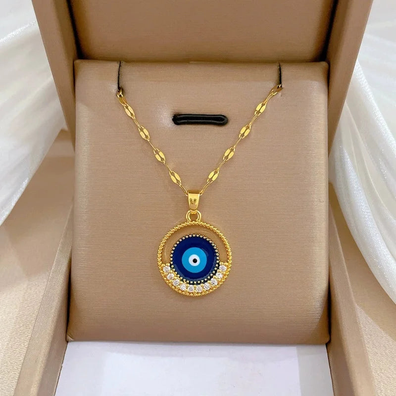 Round blue evil-eye gold-tone pendant with crystal accents displayed in a jewelry box
