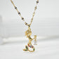 Gold-tone mermaid pendant necklace with multicolored stone accents holding a small dangling stone