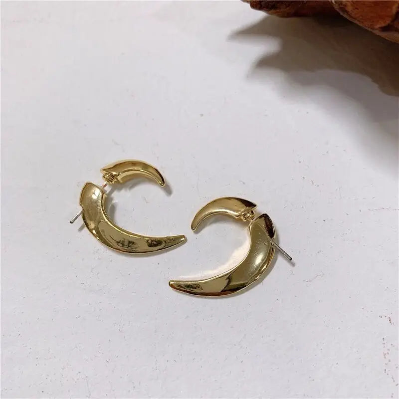 Pair of gold-tone crescent hoop earrings with post backs on a light surface