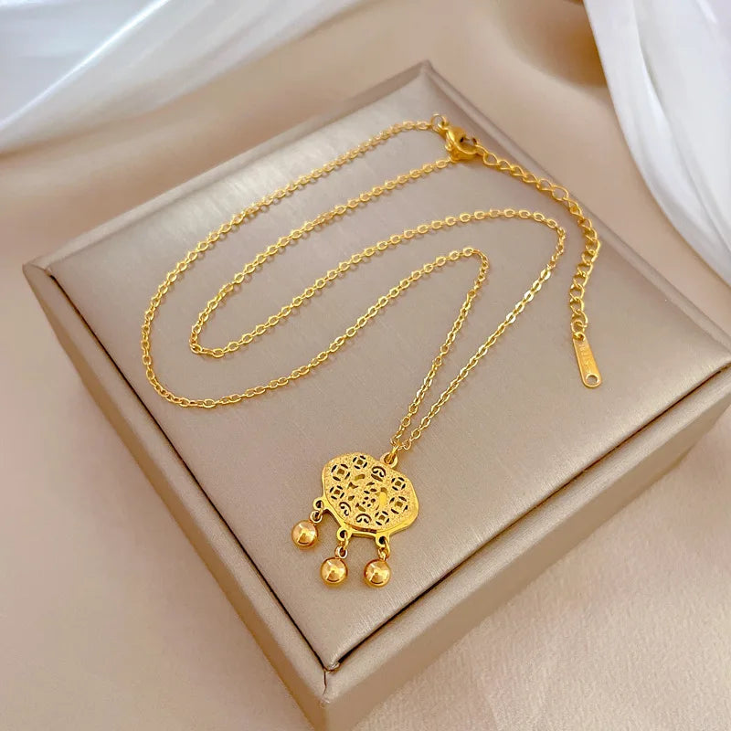 Gold-tone necklace with filigree medallion pendant and three small dangling beads, shown with lobster clasp and extender