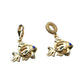 Pair of gold-tone fish charms with blue accents displayed on a floral painted background