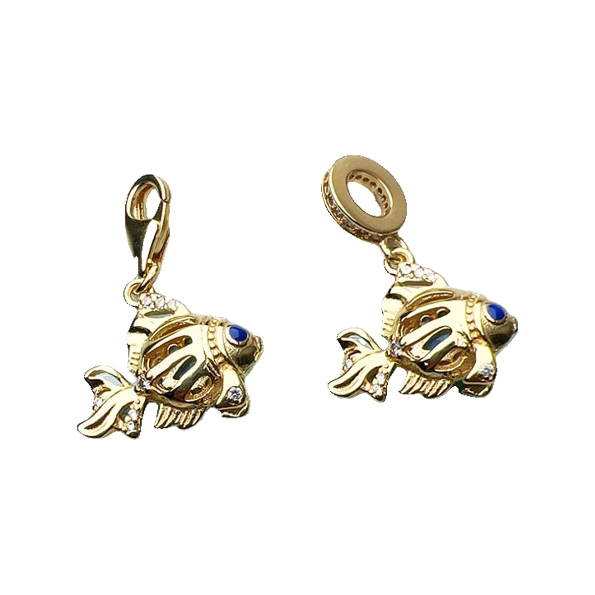 Pair of gold-tone fish charms with blue accents displayed on a floral painted background