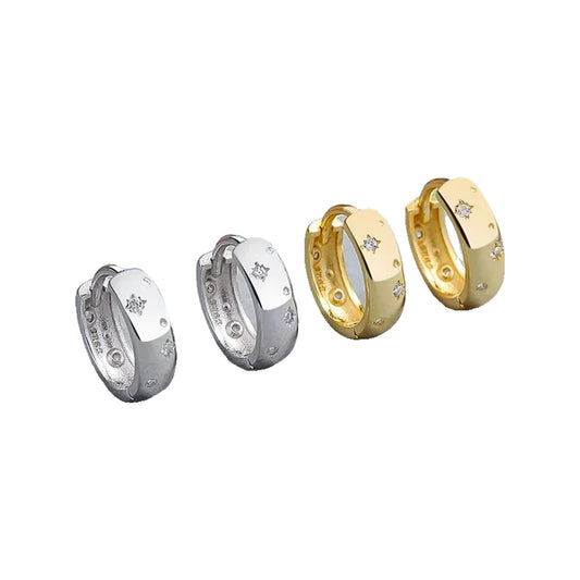 Pairs of silver-tone and gold-tone Star-Set huggie hoops displayed on a gray surface