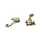 Close-up of two gold-tone fish charms with blue centers on a textured seascape backdrop